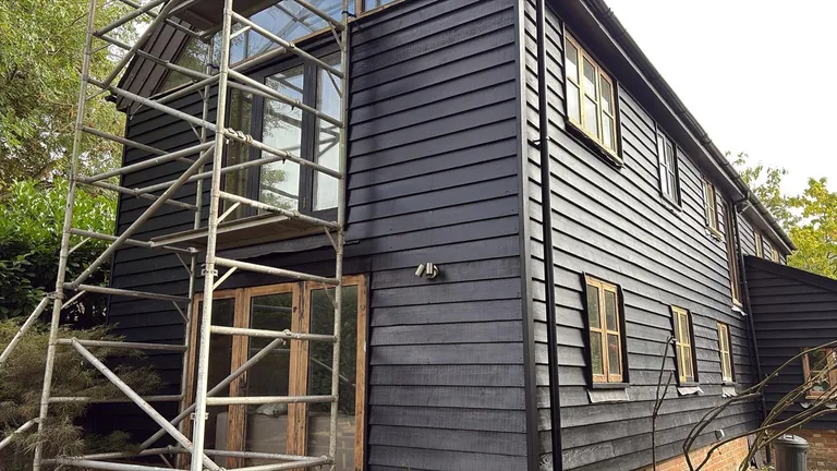 Completed dark-finish weatherboard repaint on a barn conversion at The Moor, Hawkhurst, Kent