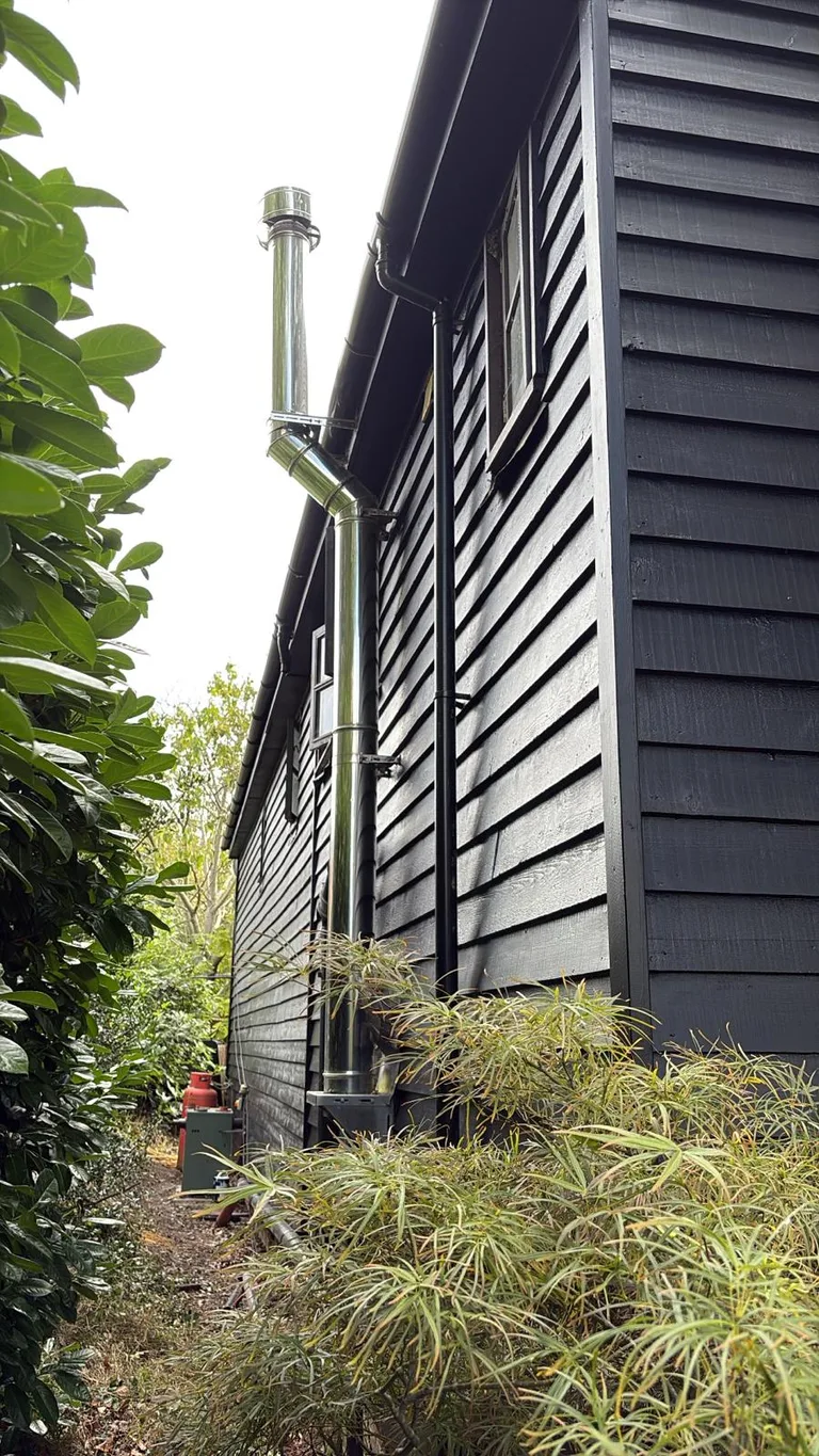 Side elevation of a Hawkhurst barn conversion showing the completed dark weatherboard finish