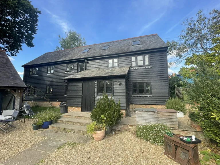 Rear view of a weathered barn conversion on The Moor, Hawkhurst, with faded dark weatherboards before restoration