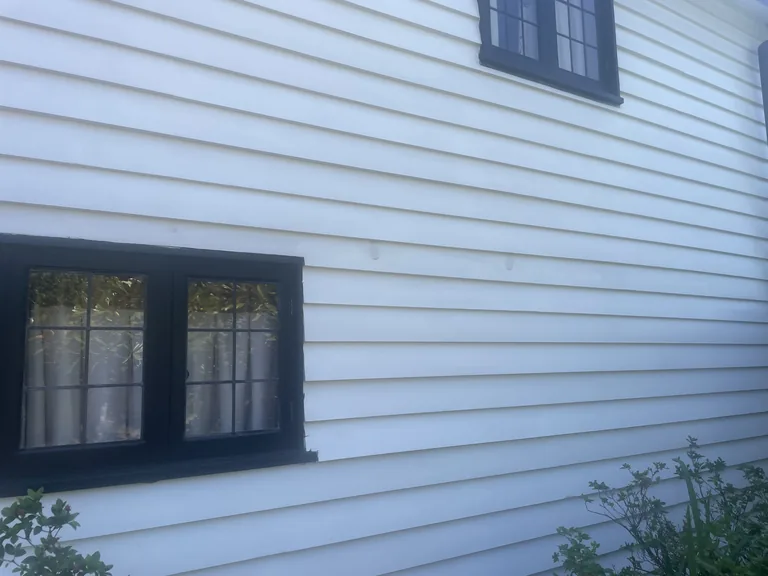 Close view of the completed white weatherboarding and contrasting dark windows on the listed oast house.