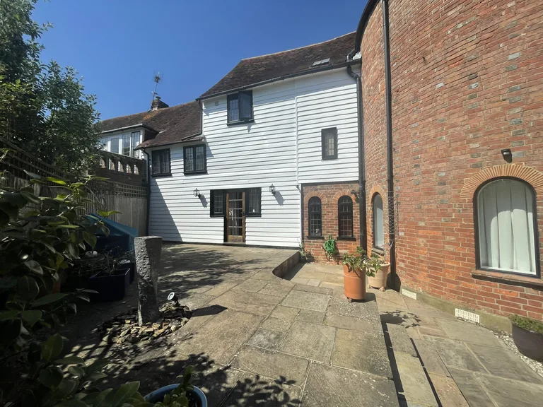Completed rear weatherboarded elevation of a Grade II listed oast house near Rye after repairs and repainting.