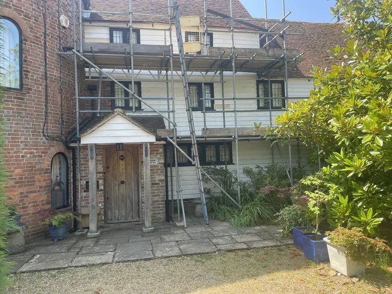 Independent scaffolding erected around the front porch of a listed oast house near Rye for weatherboard access