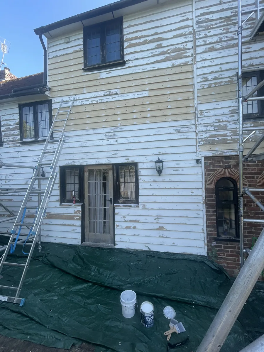 A rotten weatherboard being cut out for renewal on the rear elevation of a Grade II listed oast house near Rye, with sound boards left in place