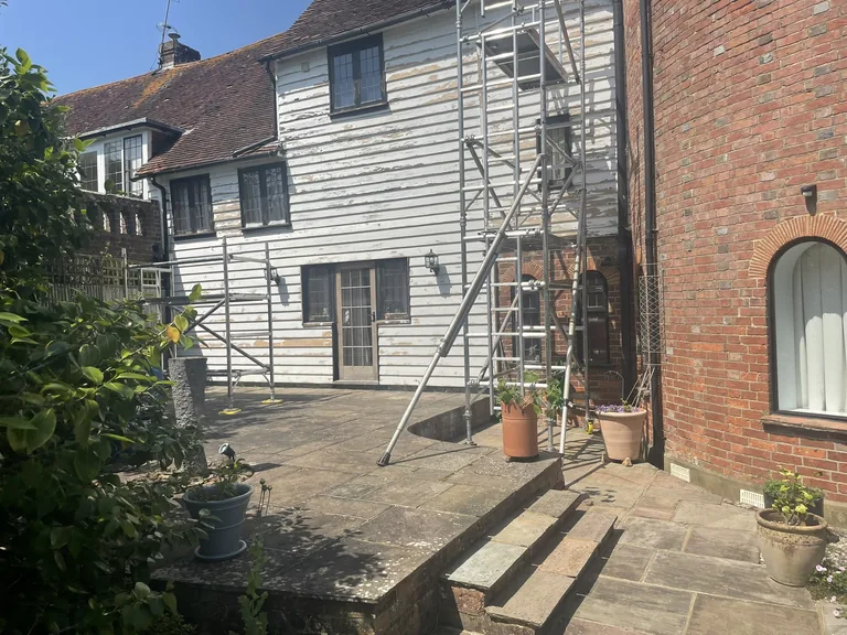 Rear of a Grade II listed oast house in Northiam near Rye showing weathered weatherboards before restoration