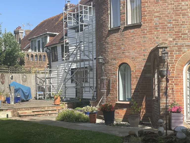 Brick oast roundel beside the weatherboarded elevation while restoration work is in progress.