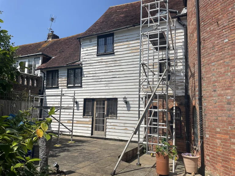 Rear elevation of a Grade II listed oast house before restoration, showing extensive failure of the existing coating.