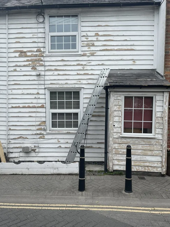 Flaking paint on the weatherboards of a Grade II listed property on Bridewell Lane, Tenterden, before work