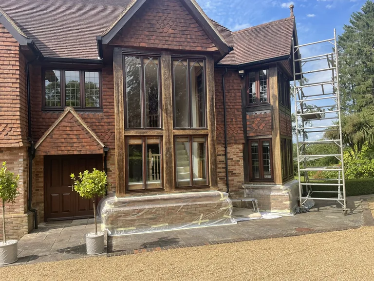 Applying Osmo clear varnish to oak window frames at a Hawkhurst property