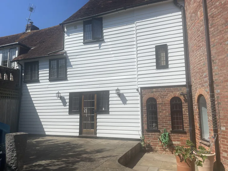 Restored rear weatherboarded elevation beside the brick oast building near Rye.