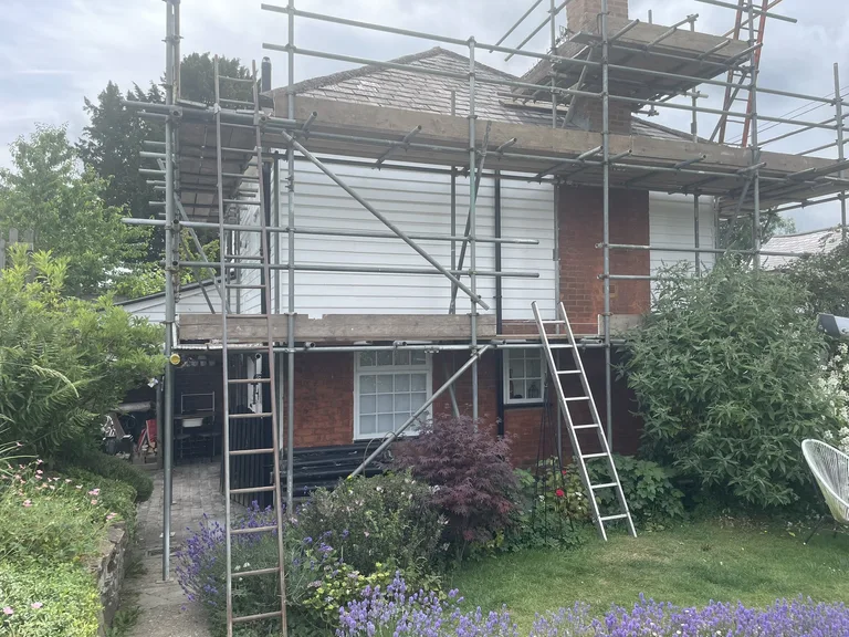 Freshly painted white weatherboards on a Ticehurst house with scaffold still in place during restoration