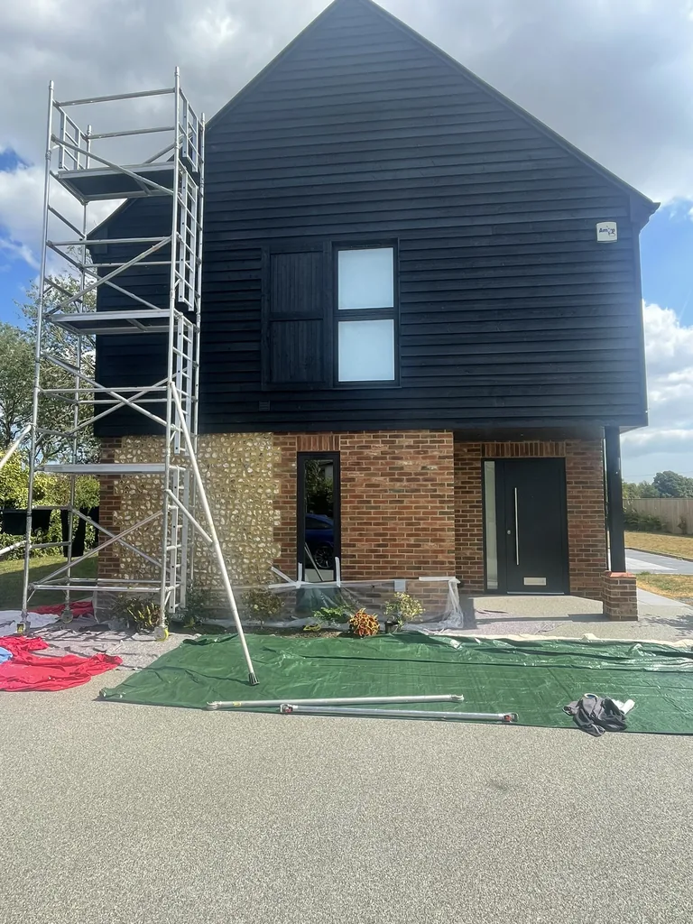 Mobile tower scaffold at the gable with the resin driveway and planted borders covered and protected below during high level weatherboard maintenance