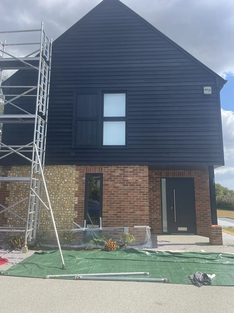 Front elevation of the completed modern weatherboarded home with the driveway and borders still covered during the work