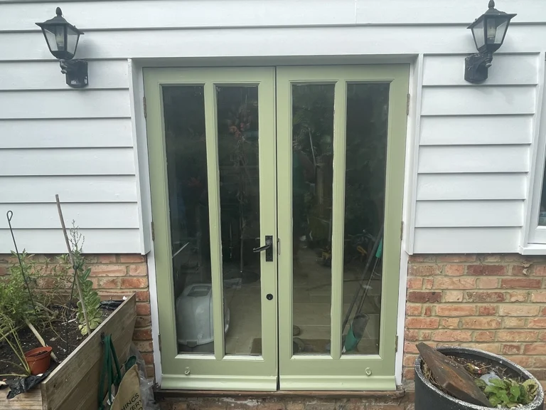 Finished green door and surrounding white weatherboarding in Boughton Monchelsea
