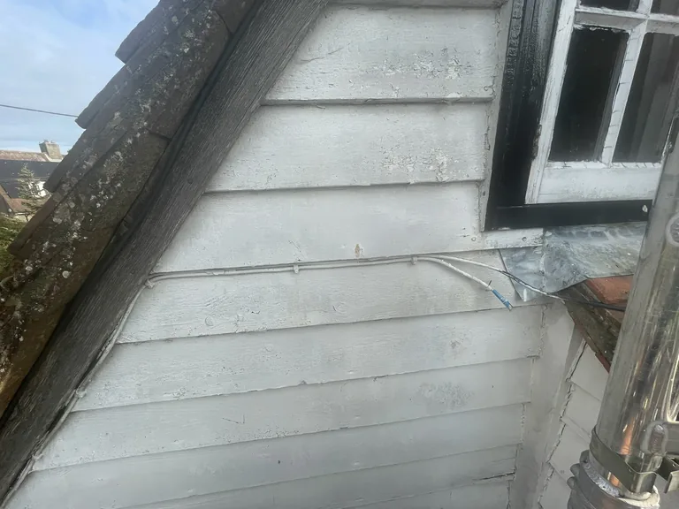 Tired, weathered weatherboards before repair on a cottage in Mountfield, East Sussex